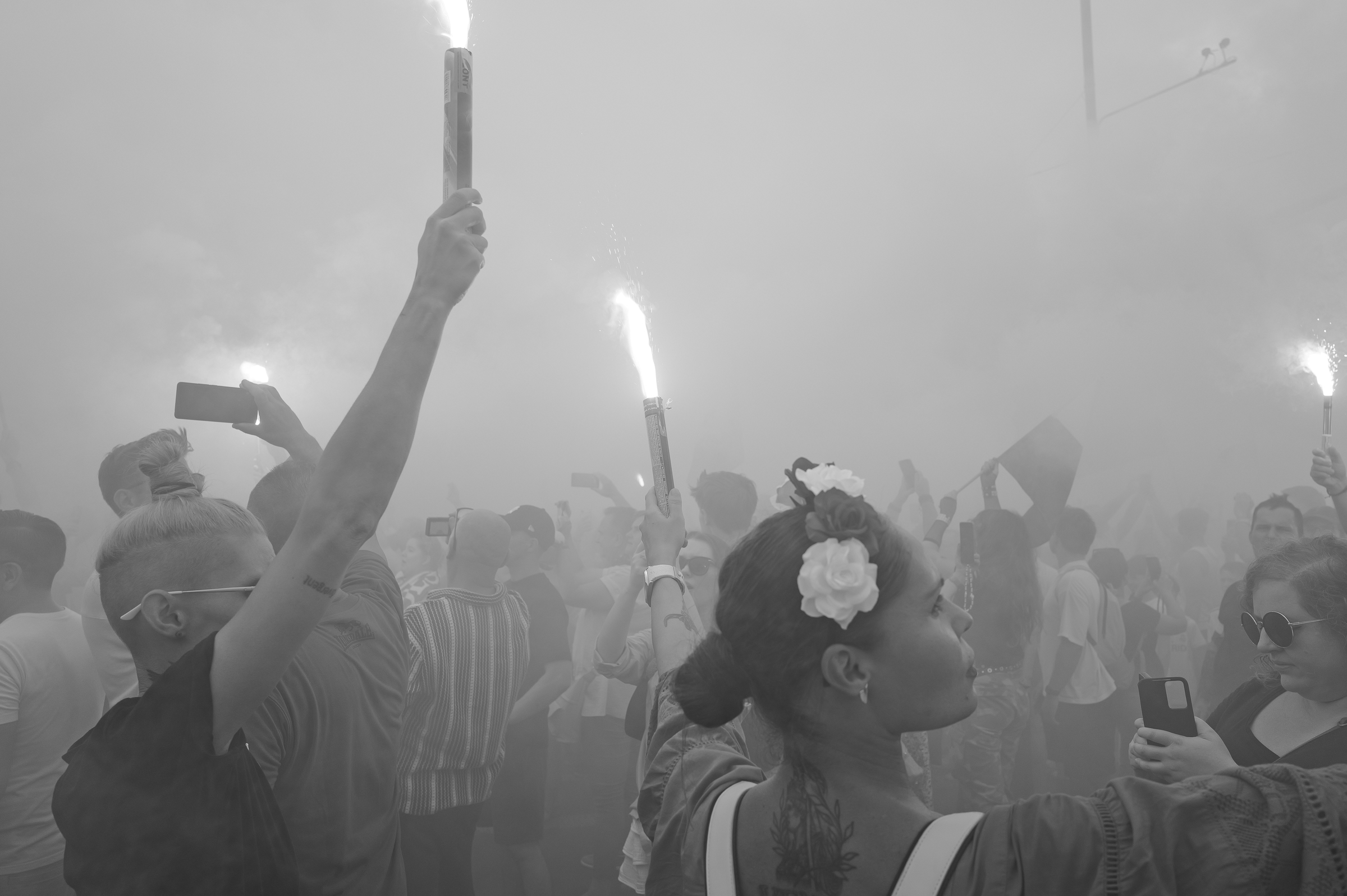 fot. Maciej Niedzielski, Dwie kobiety trzymające race w tłumie podczas godziny W w Warszawie, czarno białe zdjęcie wykonane Leica Q3