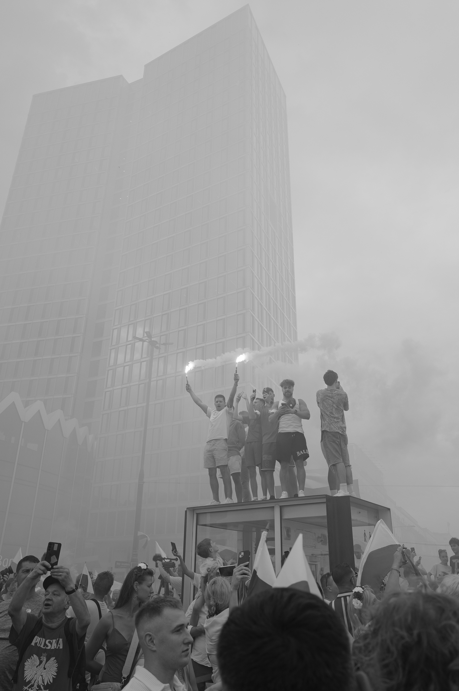 fot. Maciej Niedzielski, Mężczyźni z racami stojący na przystanku w warszawie podczas obchodów godziny W, czarno biale zdjecia wykonane Leica Q3